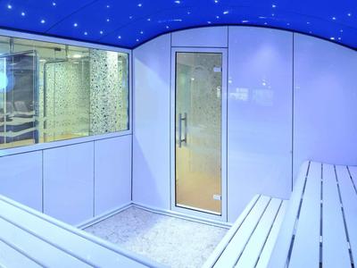 Lichte sauna met witte houten banken en glasruit naar de buitensauna