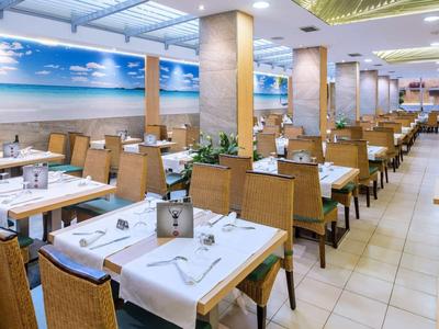 Licht restaurant met rijen tafels en houten meubels, muur versierd met strandafbeelding