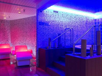 Een stijlvol verlichte wellnessruimte met bubbelbaden en ligstoelen.