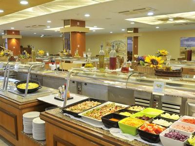 Groot buffet met verschillende verse salades en warme gerechten in een helder restaurant.