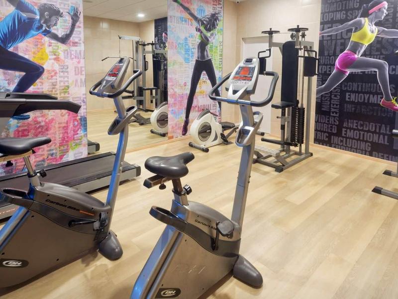 Moderne sportschool met fitnessapparatuur, versierd met sportmuurschilderingen en houten vloer.