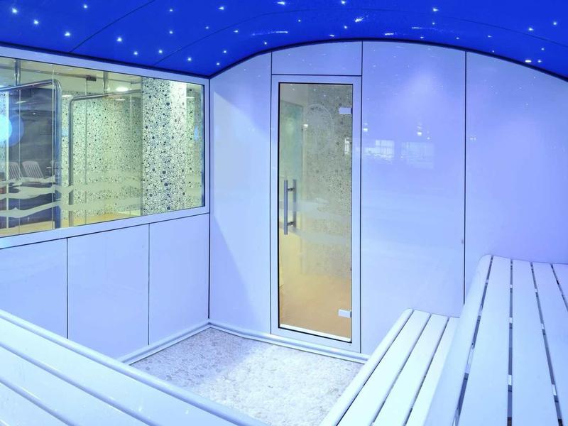 Lichte sauna met witte houten banken en glasruit naar de buitensauna