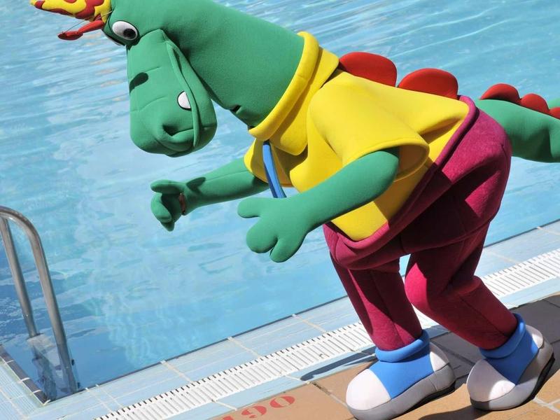 Kleurrijk drakenfiguur in kleding naast een hotelzwembad.