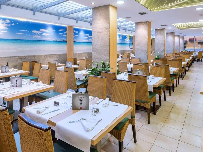 Licht restaurant met rijen tafels en houten meubels, muur versierd met strandafbeelding