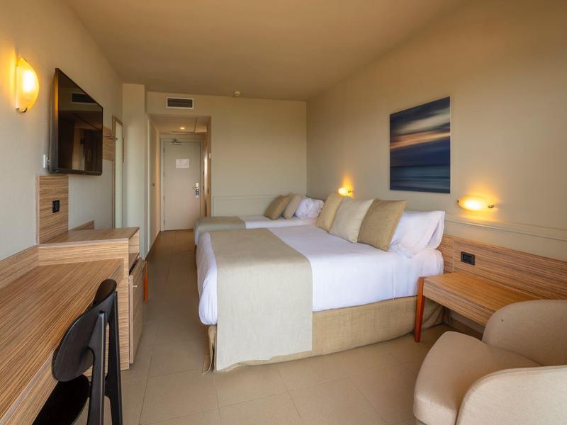 Habitación de hotel moderna con cama doble, escritorio, sillón y decoración mínima.