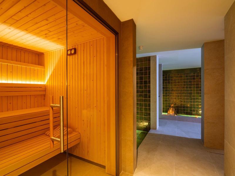 Área interior moderna con sauna de madera y zona de relajación adyacente en el hotel.