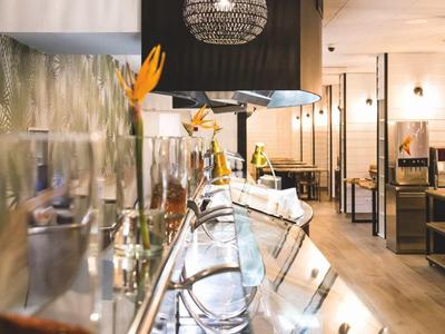 Moderner Restaurantbereich mit beleuchteten schwarzen Korblampen, Holzmöbeln und Glasservierstation.