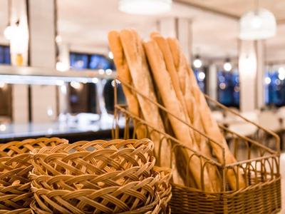 Verschiedene Brotkörbe aus Holz und Metall mit langen Baguettes in hellem Licht.
