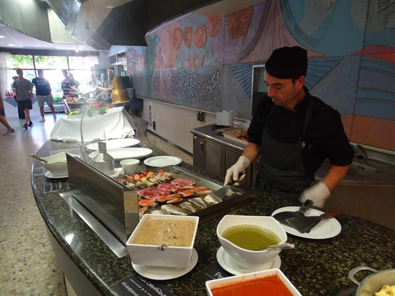 Chef prepares burgers and fries at an open kitchen in a modern restaurant.