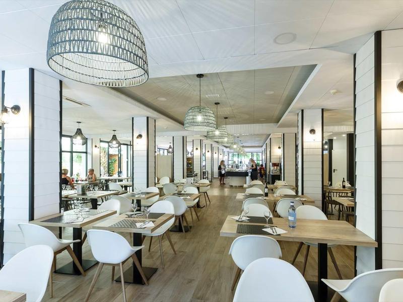 Spacious, bright modern dining area with wooden and white chairs and tables.