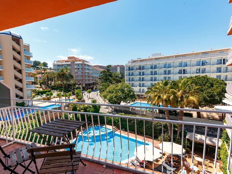 View from balcony over pool and surrounding hotel buildings under clear sky.