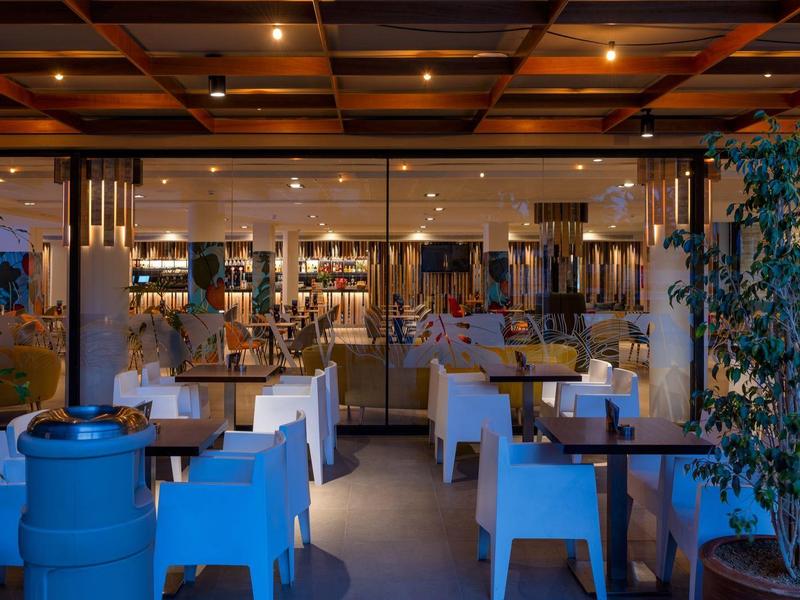 Gemütliches, warm beleuchtetes Restaurant mit gedeckten Tischen und Pflanzen.