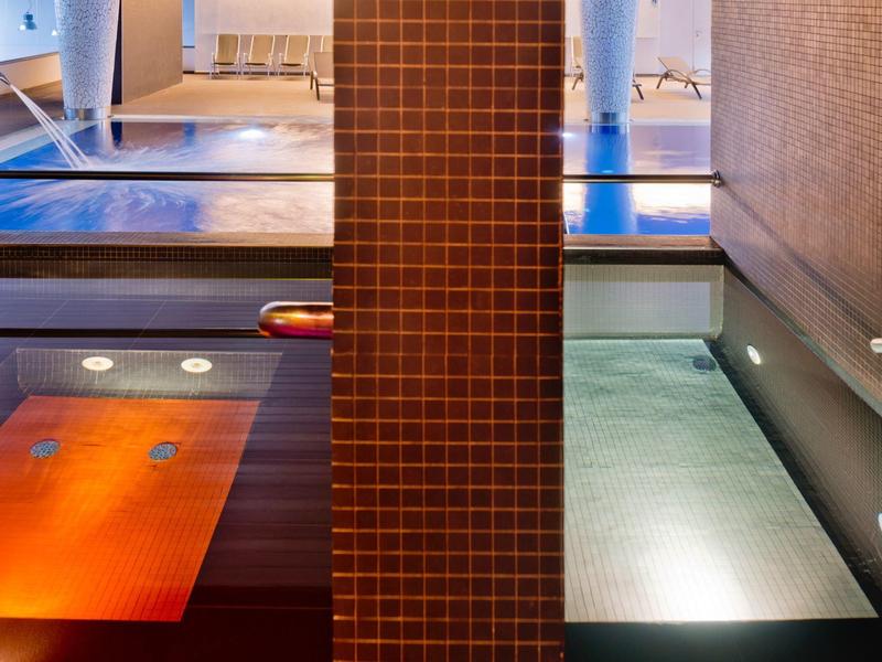 Innenraum mit zwei quadratischen Pools, getrennt durch eine rot gekachelte Wand, modernes Design.