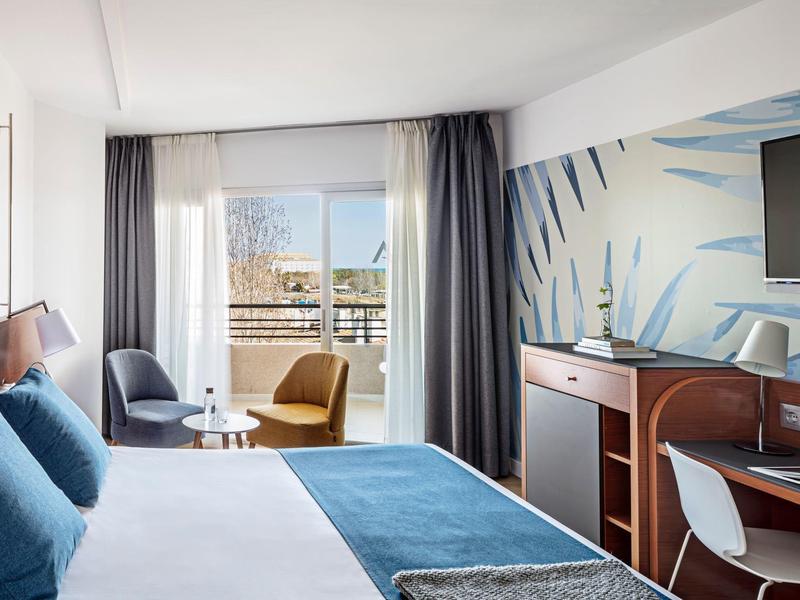 Modernes Hotelzimmer mit Doppelbett, blauen Akzenten, Balkon und bunter Wandgestaltung.
