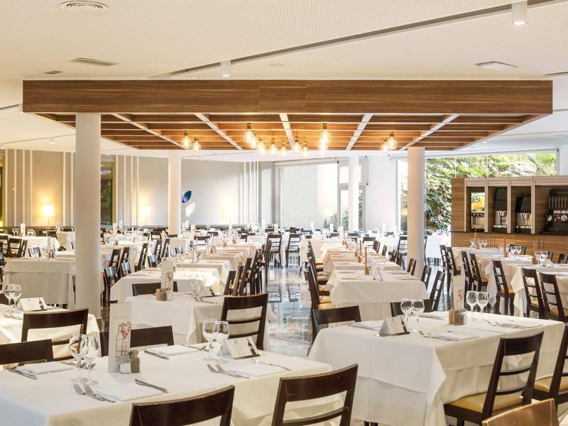 Großer heller Speisesaal mit weiß gedeckten Tischen und Holzmöbeln, modern und einladend gestaltet.