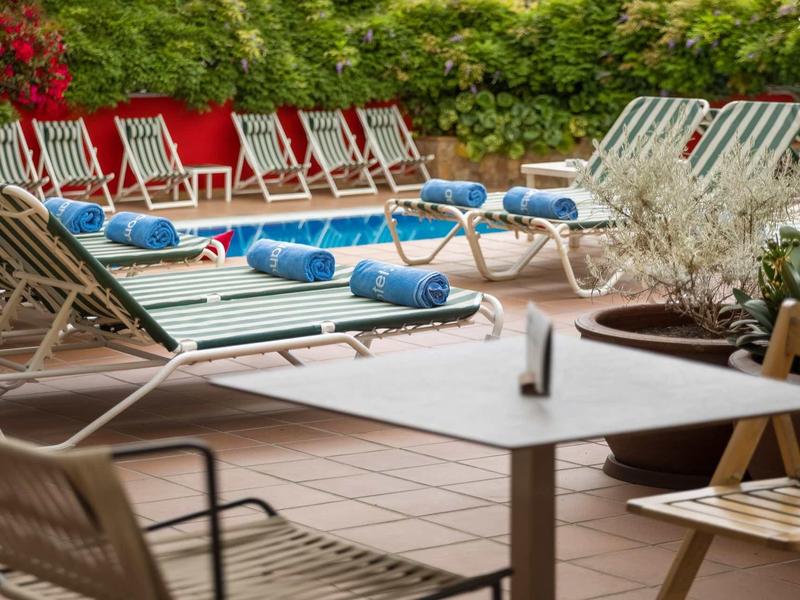 Terraza con sillas y mesas, al fondo tumbonas con toallas azules.