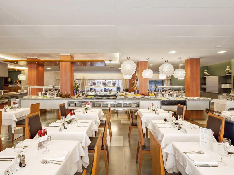 Restaurante de hotel luminoso con manteles blancos, muebles de madera y ambiente acogedor.