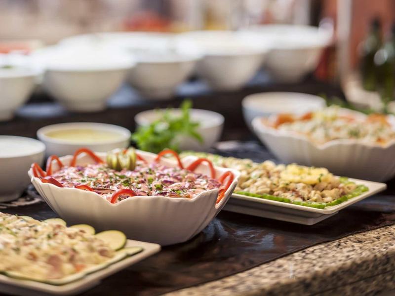 Buffet con diversas ensaladas y aperitivos en cuencos blancos sobre un mostrador.