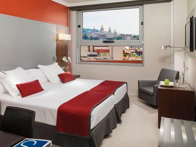 Modernes Hotelzimmer mit großem Doppelbett, weißen und roten Bettbezügen, Fenster mit Stadtblick.