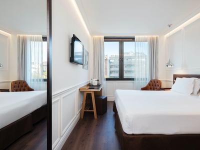 Helles, modernes Schlafzimmer mit großem Bett, Holzfußboden und Fenster mit Stadtblick.