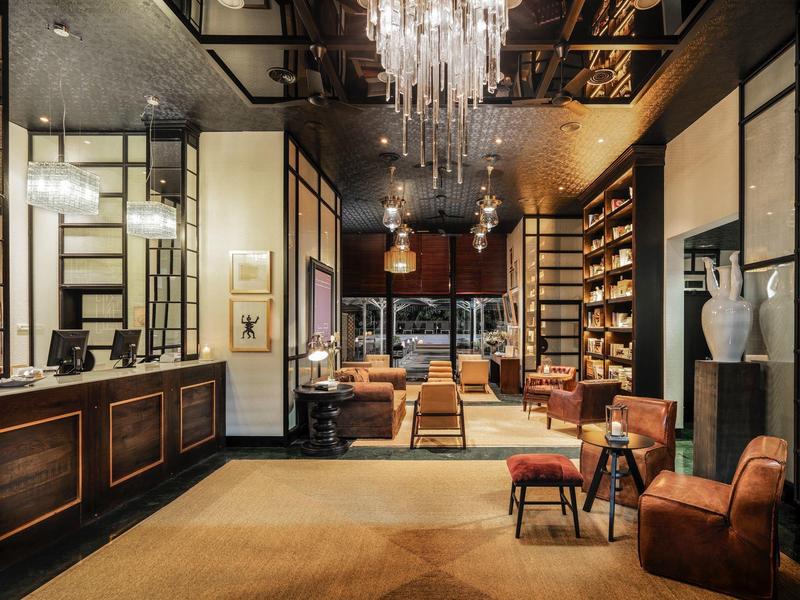 Elegante Hotellobby mit Kronleuchtern, Ledersesseln, Teppichboden und Holzmöbeln.