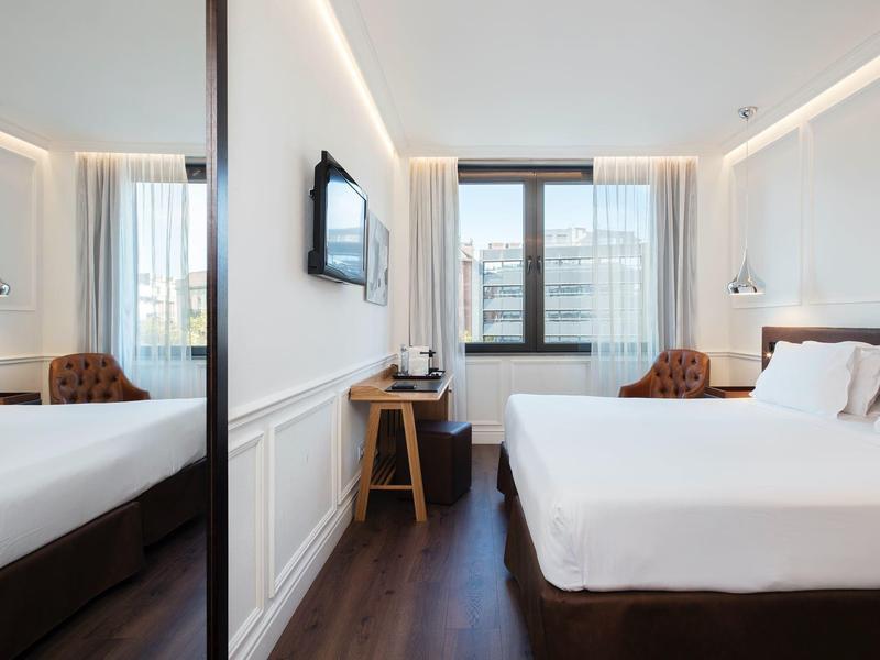 Helles, modernes Schlafzimmer mit großem Bett, Holzfußboden und Fenster mit Stadtblick.