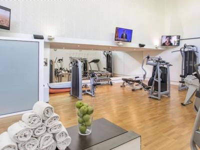 Heller Fitnessraum mit modernen Geräten, Handtüchern und einer Pflanze in der Ecke.