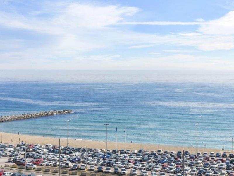 Strand mit Sand, vielen geparkten Autos und blauem Himmel mit Wolken über dem Meer.