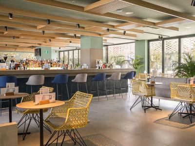 Área de bar de hotel moderna con sillas y mesas acogedoras en luz cálida.