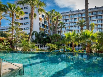 Hotel mit Außenpool und Palmen unter blauem Himmel