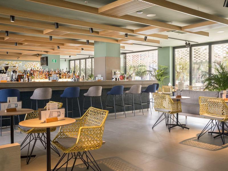 Área de bar de hotel moderna con sillas y mesas acogedoras en luz cálida.