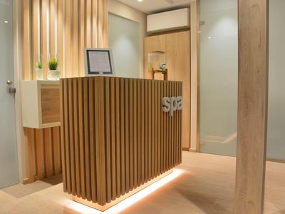 Moderne spa-receptie met houten balie en zachte verlichting in een rustige omgeving.