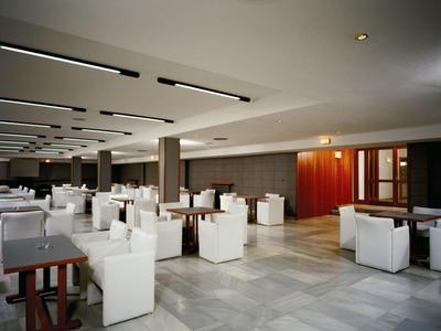 Grande salle à manger moderne avec des chaises blanches et des tables en bois foncé.