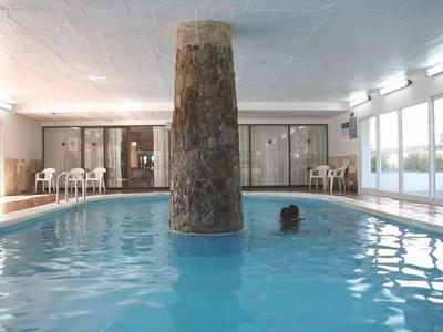 Innenpool mit großem Natursteinpfeiler und Sitzgelegenheiten im Hintergrund.