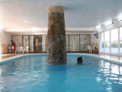 Piscine intérieure avec eau bleue, pilier central et grandes fenêtres sur le côté.