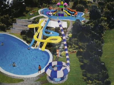 Parc aquatique avec plusieurs toboggans menant à différentes piscines, entouré de verdure.