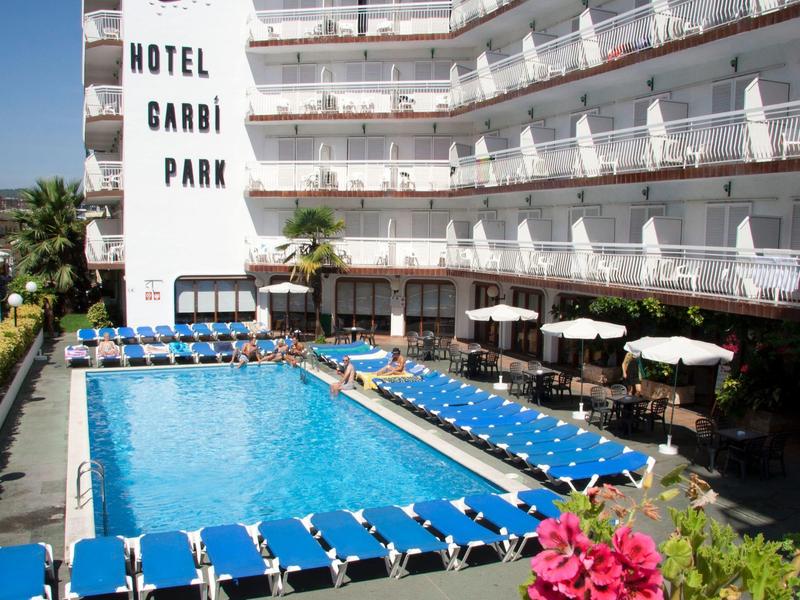 Hôtel avec piscine et chaises longues bleues, bâtiment à plusieurs étages avec balcons