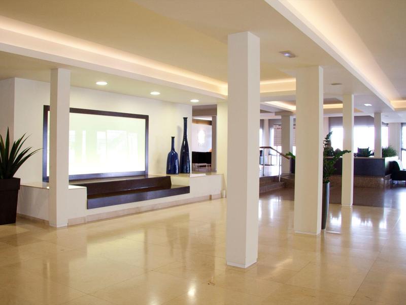 Espace lounge d'hôtel lumineux avec sol poli, colonnes blanches et sièges.