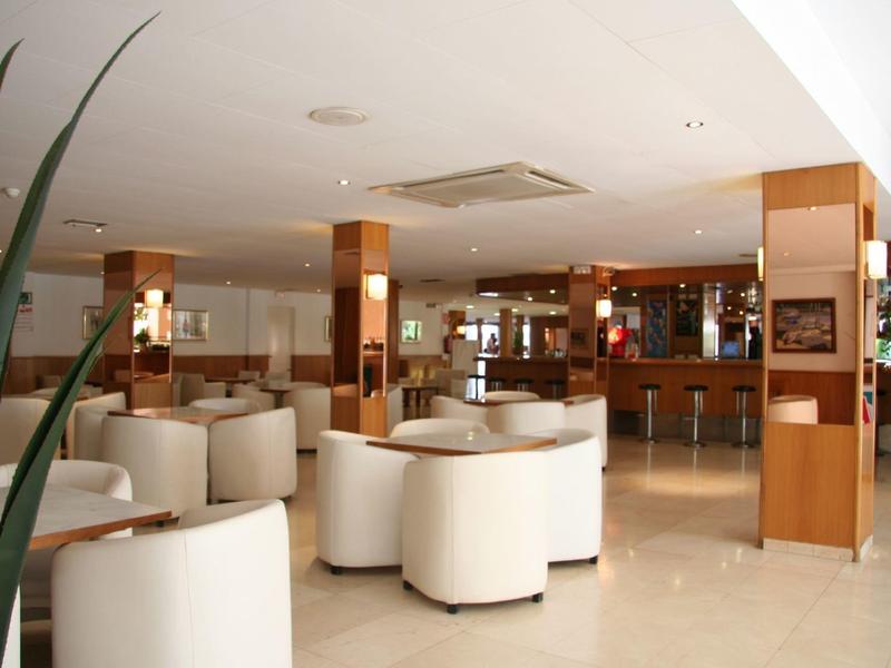 Bar d'hôtel moderne avec fauteuils blancs, meubles en bois et ambiance lumineuse et ouverte.