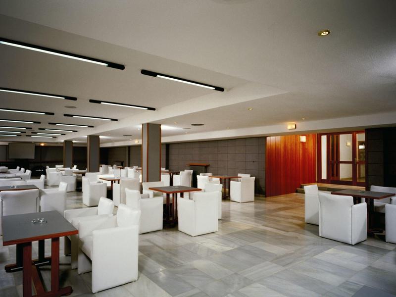 Grande salle à manger moderne avec des chaises blanches et des tables en bois foncé.