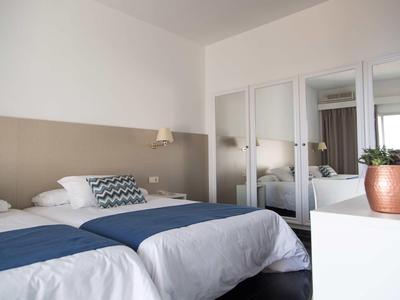 Moderne hotelkamer met twee eenpersoonsbedden, blauwe dekens en grote spiegelkast