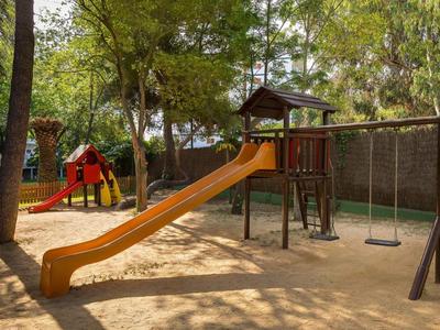 Kinderspeelplaats met glijbaan, schommels en klimtoestellen in een zonnig buitenterrein.
