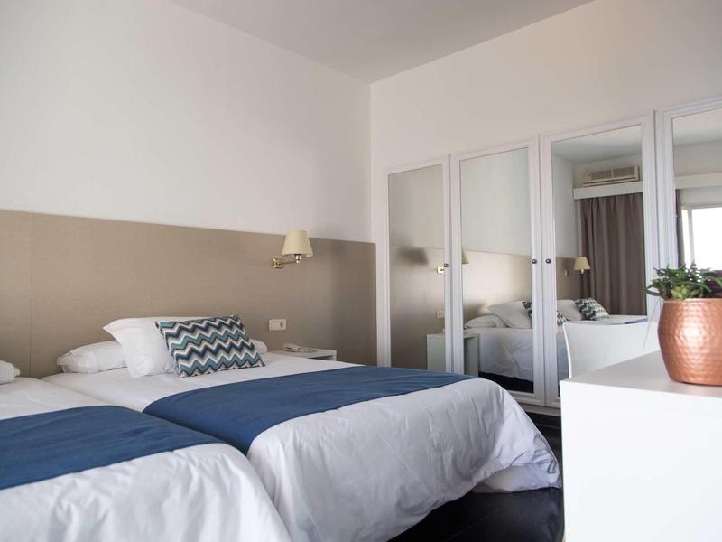 Moderne hotelkamer met twee eenpersoonsbedden, blauwe dekens en grote spiegelkast