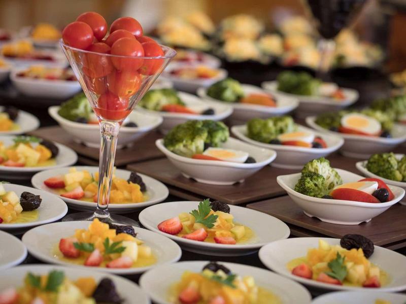 Verscheidenheid aan kleine hapjes en salades op witte borden bij een buffet.