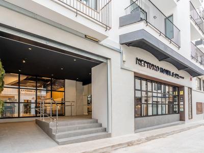 Moderní vchod do hotelu s velkými okny a betonovým schodištěm.