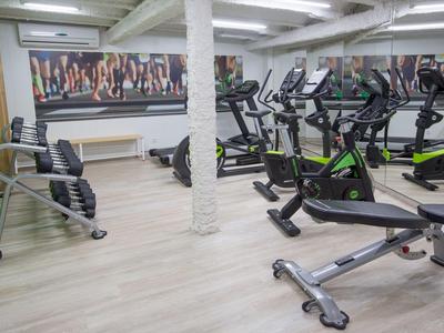 Moderner Fitnessraum mit Cardiogeräten und Hanteln in einem Hotel.