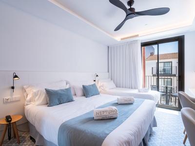 Modernes Hotelzimmer mit großem Bett, hellen Wänden, Balkon und Deckenventilator.