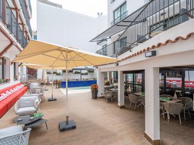 Hotelové nádvoří s bazénem, slunečníky a pohodlnými židlemi k odpočinku.