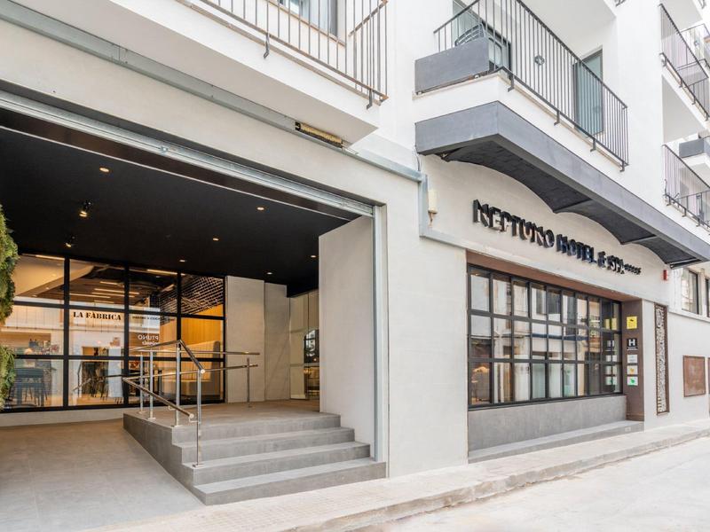 Moderní vchod do hotelu s velkými okny a betonovým schodištěm.