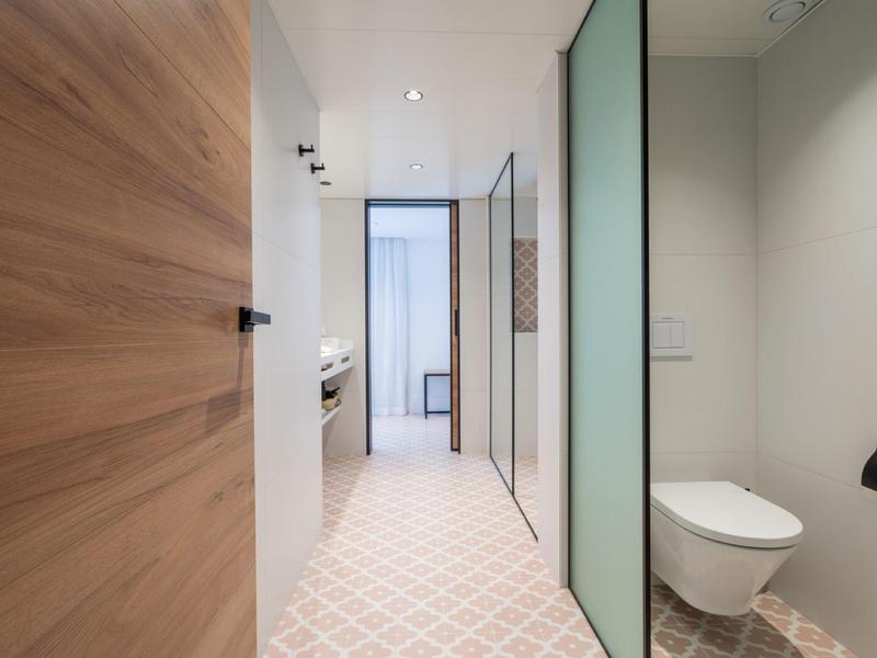 Moderní koupelna s závěsným záchodem a rozdělovacími skleněnými panely.